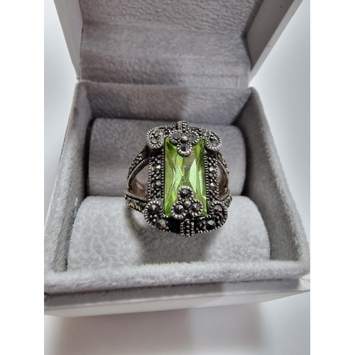 385 - A good quality ornate 925 silver dress ring inset with a large baguette cut green glass stone surrou... 
