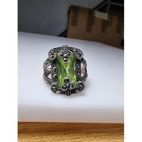 385 - A good quality ornate 925 silver dress ring inset with a large baguette cut green glass stone surrou... 