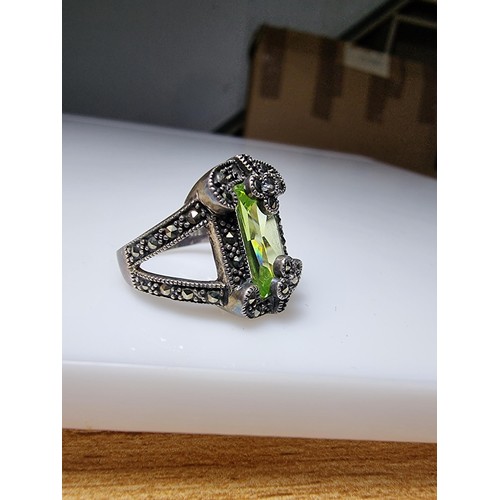 385 - A good quality ornate 925 silver dress ring inset with a large baguette cut green glass stone surrou... 