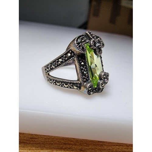 385 - A good quality ornate 925 silver dress ring inset with a large baguette cut green glass stone surrou... 