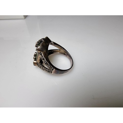 385 - A good quality ornate 925 silver dress ring inset with a large baguette cut green glass stone surrou... 