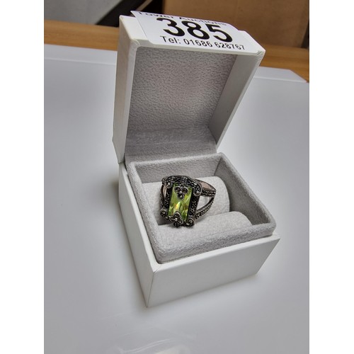 385 - A good quality ornate 925 silver dress ring inset with a large baguette cut green glass stone surrou... 