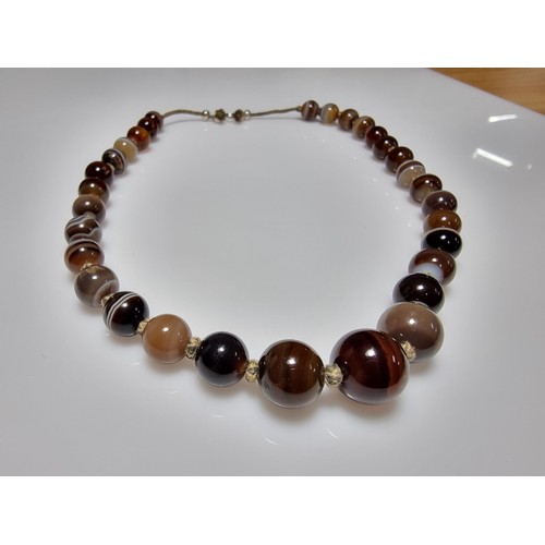 386 - A pretty hand knotted beaded necklace with banded agate beads, presenting good colours, in good clea... 