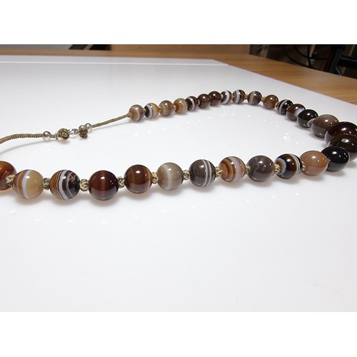 386 - A pretty hand knotted beaded necklace with banded agate beads, presenting good colours, in good clea... 