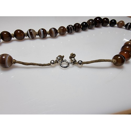 386 - A pretty hand knotted beaded necklace with banded agate beads, presenting good colours, in good clea... 