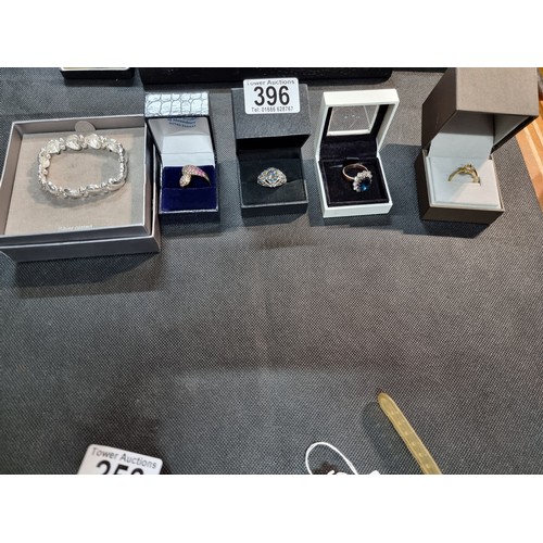 396 - A quantity of boxed dress rings and a silver plated bracelet to include an ornate ring with an aura ... 