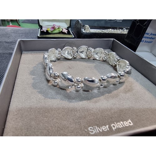 396 - A quantity of boxed dress rings and a silver plated bracelet to include an ornate ring with an aura ... 