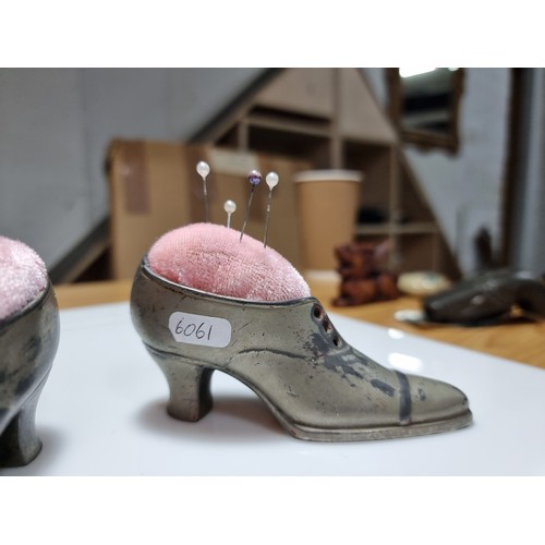 402 - A pair of metal shoe formed pin cushions with a quantity of pins in good clean condition. Height of ... 
