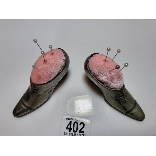 402 - A pair of metal shoe formed pin cushions with a quantity of pins in good clean condition. Height of ... 