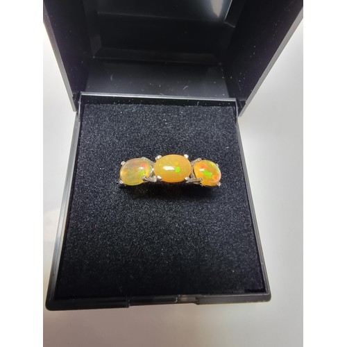 255 - A pretty 925 silver 3 stone dress ring inset with genuine Ethiopian opal stones presenting and orang... 