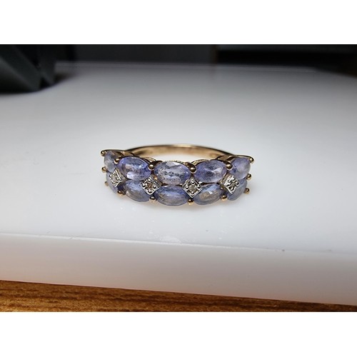 256 - A hallmarked 9ct yellow gold dress ring inset with 10 iolite gemstones and 4 small diamonds in excel... 