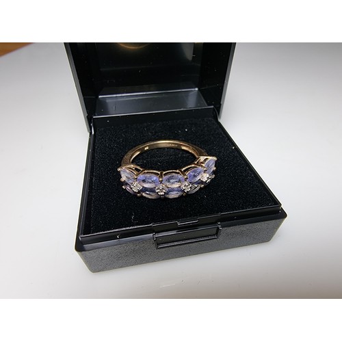 256 - A hallmarked 9ct yellow gold dress ring inset with 10 iolite gemstones and 4 small diamonds in excel... 