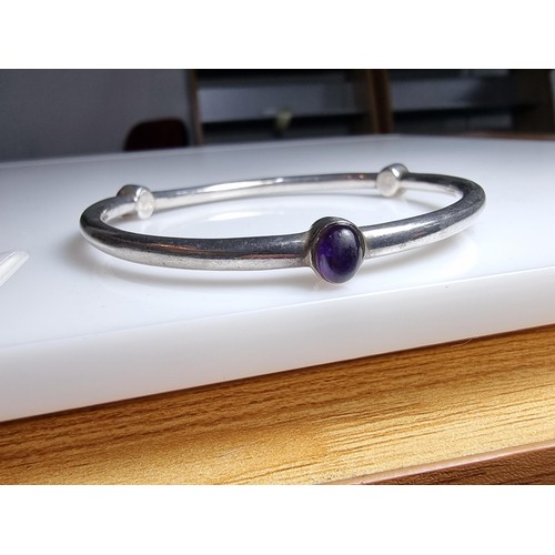 272 - A solid 925 silver bangle inset with 3 different coloured stones, red, purple and black. In excellen... 