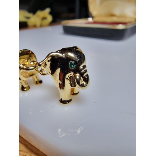 298 - A pair of unused vintage 18k gold plated elephant formed cufflinks with green gemstone eyes, never h... 