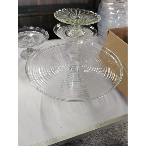 22 - A large quantity of catering glass cake stands of various sizes along with a quantity of cake domes,... 