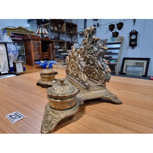 237 - A Victorian ornate brass desk stand and double inkwells featuring an ornate cherub design in good cl... 