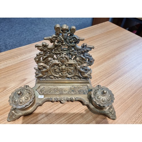 237 - A Victorian ornate brass desk stand and double inkwells featuring an ornate cherub design in good cl... 