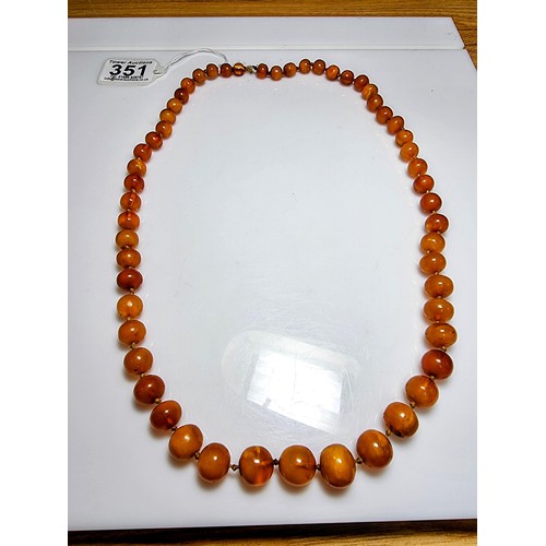 351 - A large vintage genuine egg yolk amber hand knotted beaded necklace, featuring graduated amber beads... 