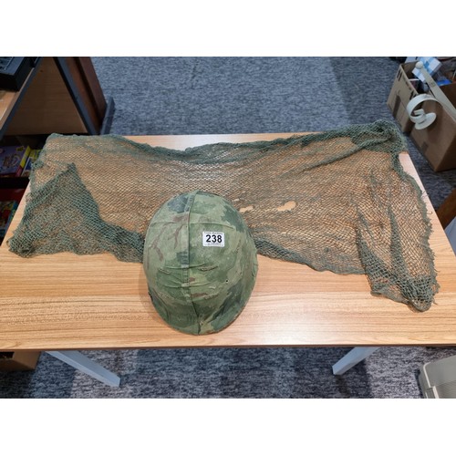 238 - A vintage military helmet with a green mesh netting, has marking to the inside of the helmet. Please... 