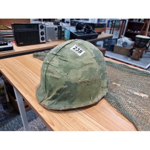238 - A vintage military helmet with a green mesh netting, has marking to the inside of the helmet. Please... 