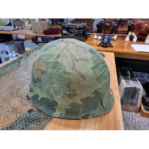 238 - A vintage military helmet with a green mesh netting, has marking to the inside of the helmet. Please... 