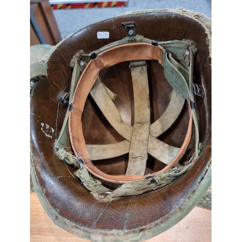 238 - A vintage military helmet with a green mesh netting, has marking to the inside of the helmet. Please... 