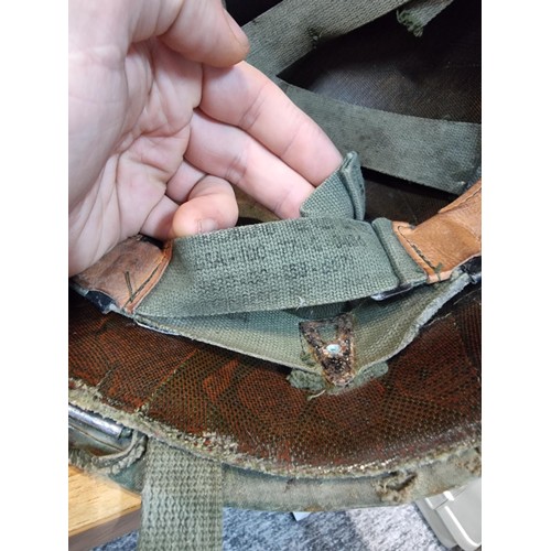238 - A vintage military helmet with a green mesh netting, has marking to the inside of the helmet. Please... 