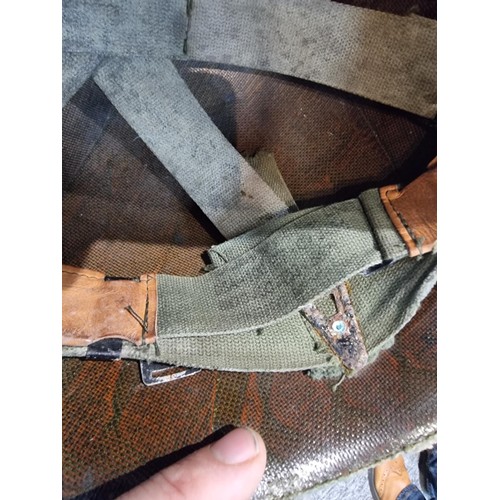 238 - A vintage military helmet with a green mesh netting, has marking to the inside of the helmet. Please... 