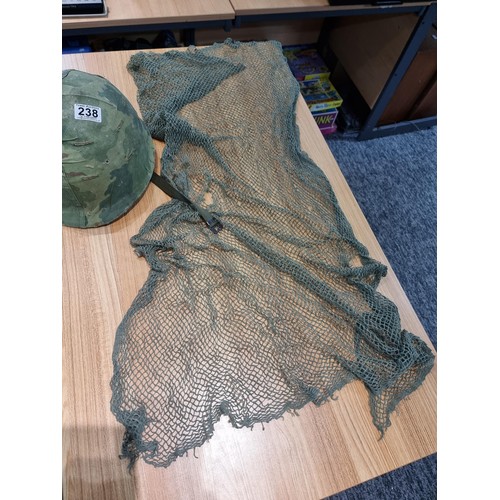 238 - A vintage military helmet with a green mesh netting, has marking to the inside of the helmet. Please... 