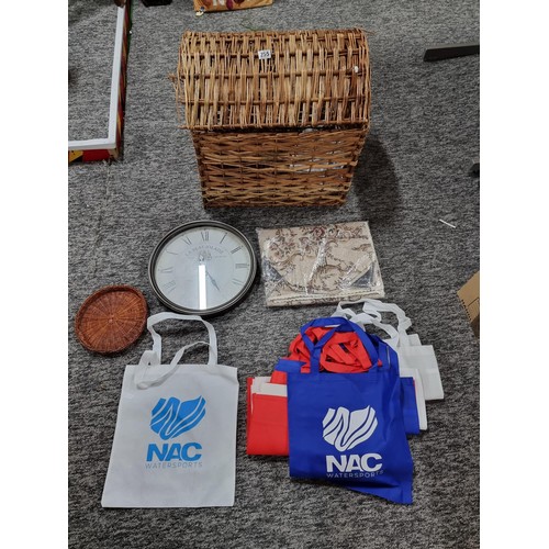 255 - A large wicker linen basket containing a large quantity of fabric tote bags, a large wall clock, a t... 