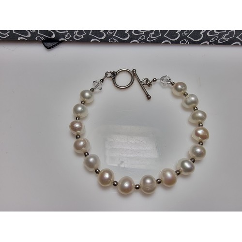 293 - A 925 silver, real pearl bracelet with glass charms to the end. In clean condition, boxed, length of... 