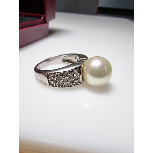 323 - A 925 silver dress ring inset with a large faux pearl and a quantity of CZ crystal stones, in good c... 
