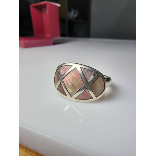 328 - A 925 silver ring inset with mother of pearl which represents good flashing colours, in good clean c... 
