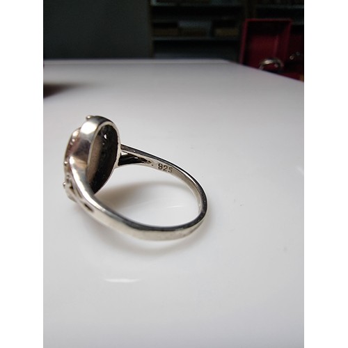 334 - A 925 silver ring with an ornate pierced design featuring mother of pearl to the centre. In clean co... 