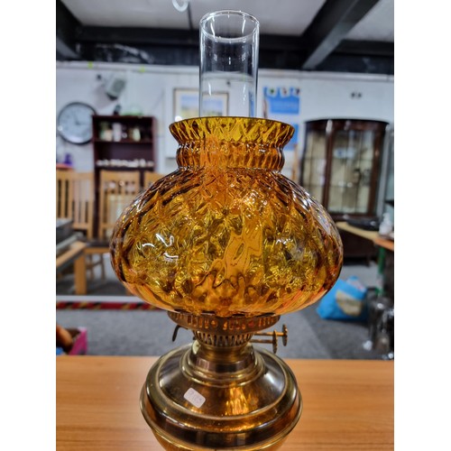 313 - A brass oil lamp with an ornate amber glass shade, in good clean condition, complete with a new wick... 