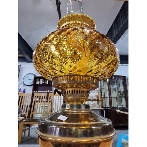 313 - A brass oil lamp with an ornate amber glass shade, in good clean condition, complete with a new wick... 