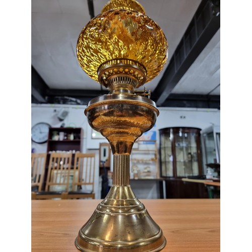 313 - A brass oil lamp with an ornate amber glass shade, in good clean condition, complete with a new wick... 