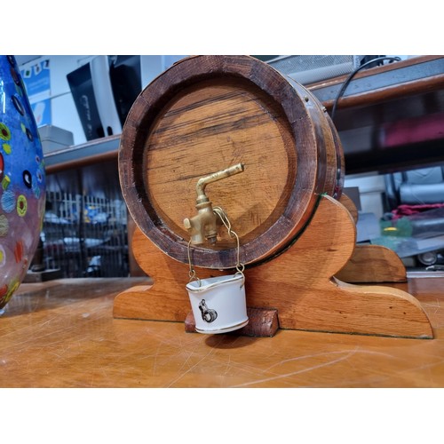 324 - A heavy solid oak copper bound barrel keg on stand along with a brass spigot and a small ceramic buc... 