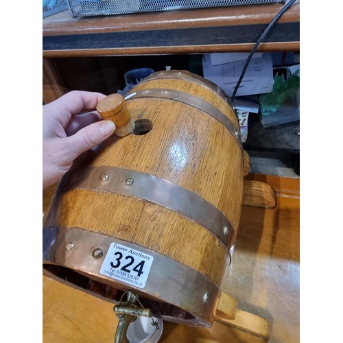 324 - A heavy solid oak copper bound barrel keg on stand along with a brass spigot and a small ceramic buc... 