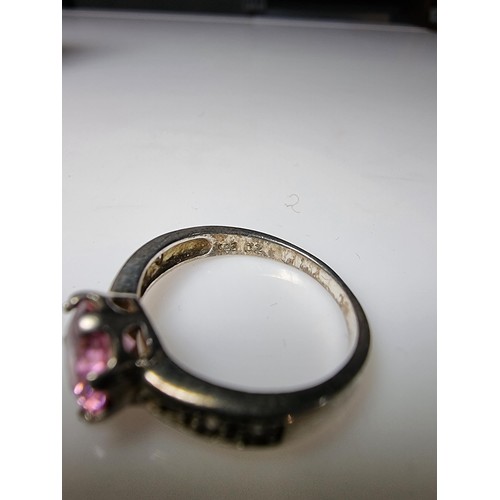 332 - An ornate 925 silver dress ring inset with a large pink crystal CZ stone and smaller clear CZ stones... 