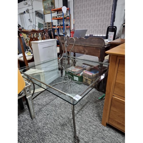 502 - Large modern glass topped coffee table with twisted metal scroll design legs along with a matching m... 