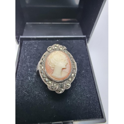 153 - A vintage sterling silver cameo ring carved out of shell surrounded by marcasite stones of a lady lo... 