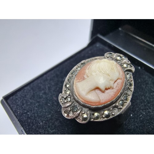 153 - A vintage sterling silver cameo ring carved out of shell surrounded by marcasite stones of a lady lo... 