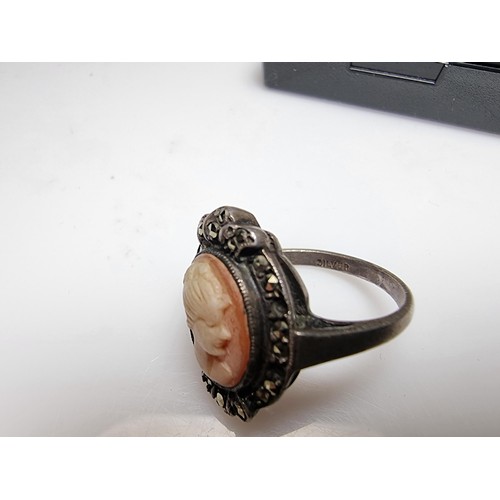 153 - A vintage sterling silver cameo ring carved out of shell surrounded by marcasite stones of a lady lo... 