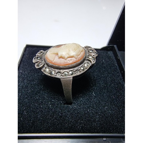 153 - A vintage sterling silver cameo ring carved out of shell surrounded by marcasite stones of a lady lo... 