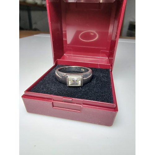 156 - A chunky 925 silver ring inset with a baguette cut CZ crystal stone. In clean condition, boxed, size... 