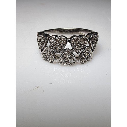 180 - A chunky 925 silver ring with a heart design inset with crystal CZ stones. In clean condition, boxed... 