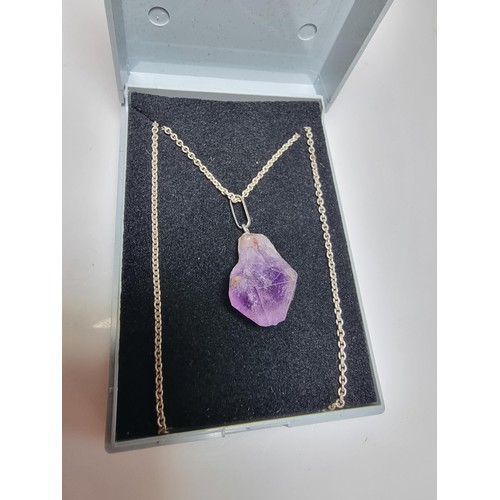 189 - A genuine amethyst rough cut pendant set on a long 23