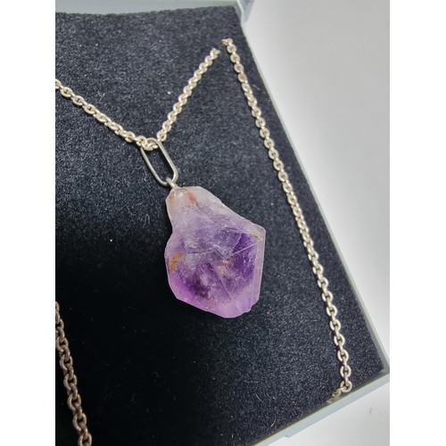 189 - A genuine amethyst rough cut pendant set on a long 23