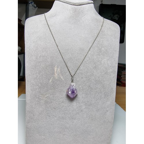 189 - A genuine amethyst rough cut pendant set on a long 23